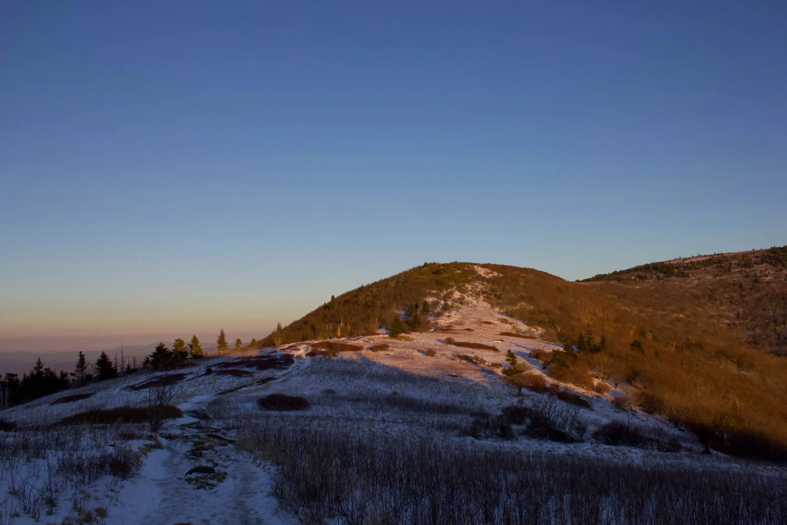 Alt Text: A scenic sunset over Roan Mountain, showcasing the silhouette of the Appalachian peaks against a vibrant sky.
